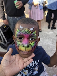 a young boy with a face painted by a face painter