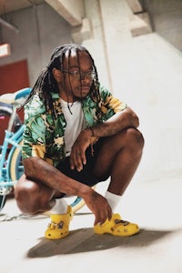 a man with dreadlocks crouching in front of a bicycle