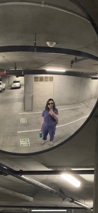 a person standing in a parking garage with a mirror