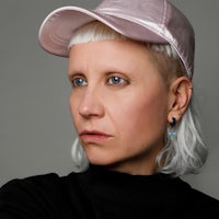 a woman with white hair wearing a pink baseball cap