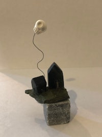 a sculpture with a skull and a house on top of a rock