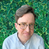 a man wearing glasses and a shirt in front of a green wall