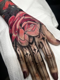 a woman's hand with a rose tattoo on it