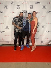 three people posing for a photo on a red carpet