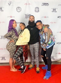 four people posing for a photo on a red carpet