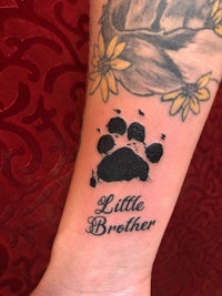 a tattoo with a paw print and the word little brother