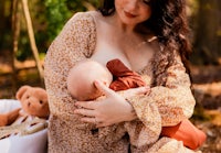 a woman breastfeeding a baby in the woods