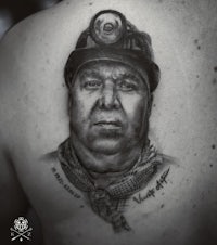 a black and white tattoo of a man wearing a hard hat