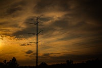 the sun is setting behind a power pole