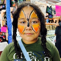 a girl with butterfly face paint at a market