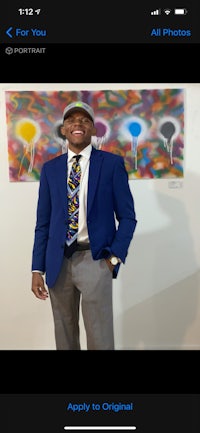 a man in a blue suit and tie is standing in front of a painting
