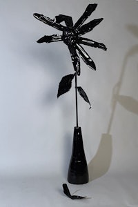 a black vase with a flower in it