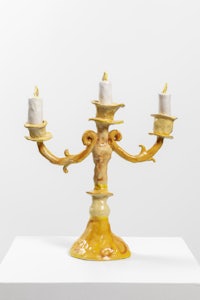 a yellow candle holder with three candles on it