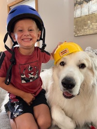 a young boy with a construction hat and a white dog