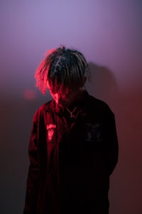 a man with dreadlocks standing in front of a red light
