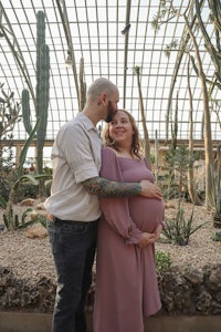 a pregnant couple standing in front of cactus plants