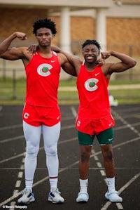 two young men posing for a photo on a track