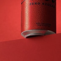 a red can of soda sitting on top of a red background