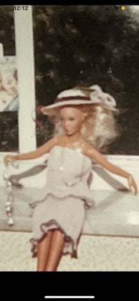 a photo of a barbie doll sitting on a window sill