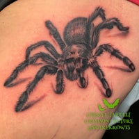 a black and grey spider tattoo on a woman's thigh