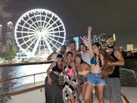 a group of people posing on a boat in front of a ferris wheel