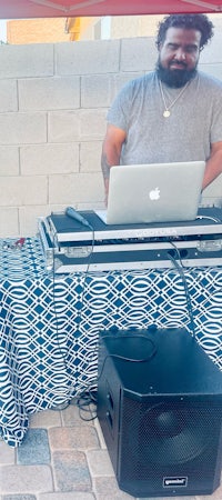 a man with a beard standing next to a laptop