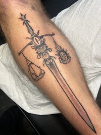 a tattoo of a sword on a man's leg