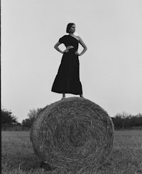 a woman standing on top of a hay bale