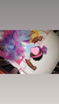 a baby dressed in a tutu laying on a bed