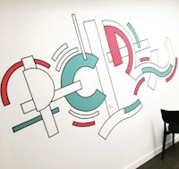 an office with a colorful wall mural and a chair