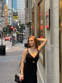 a woman in a black dress posing in front of a building