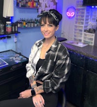 a woman sitting on a chair in a tattoo shop