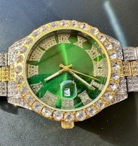 a green and gold watch with diamonds on it