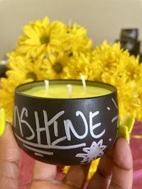 a person holding a candle with the word shine written on it