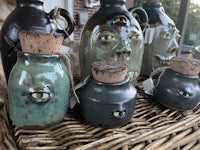 a group of jugs with faces on them on a wicker basket
