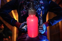 a woman holding a red bottle with a red light in it
