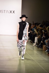 a man in a hat walks down the runway