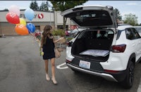 a woman opens the trunk of a suv with balloons in it