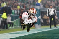 a san francisco 49ers football player is diving for the ball