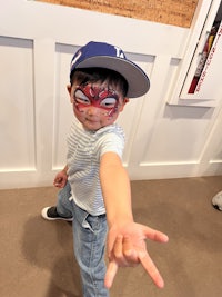 a young boy with a spider - man face painted on his face