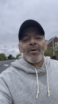 a man in a gray hoodie taking a selfie