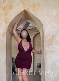 a woman in a burgundy dress posing in an archway