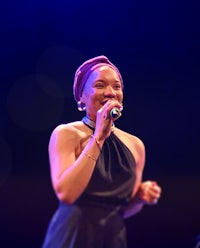 a woman in a black dress singing into a microphone