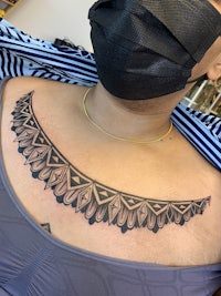 a woman wearing a mask with a tattoo on her chest