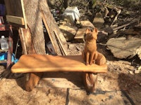 a wooden bench with a carving of a cat on it
