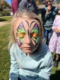 a little girl with a butterfly painted on her face