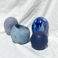 three blue ceramic vases on a white surface