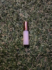 a white tube of lipstick sitting on the grass