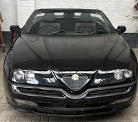a black alfa romeo convertible parked in front of a building