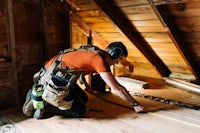 a man working on a wooden floor in an attic
